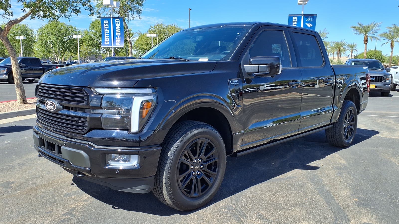 Black 2025 Ford F-150 Platinum SuperCrew pickup truck parked on a dealer lot, front left three-quarter view