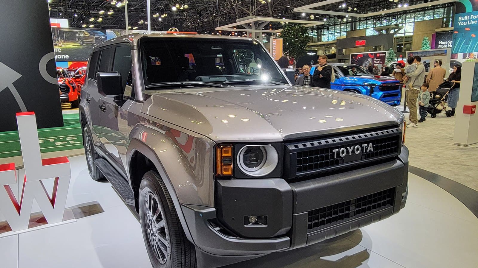 Gray 2024 Toyota Land Cruiser SUV on an auto show turntable, front left three-quarter view