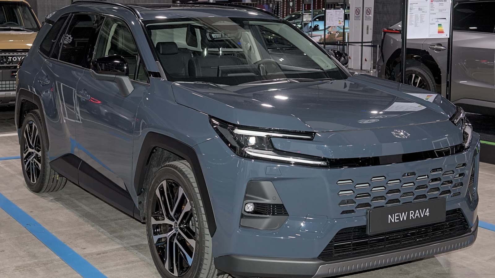 White Toyota RAV4 Core Plug-in Hybrid crossover at an auto show, front left three-quarter view